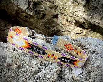 May include: A beaded bracelet with a geometric pattern in shades of beige, black, white, orange, and purple. The bracelet has a silver clasp.