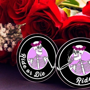 Op de afbeelding: Twee ronde stickers in zwart en wit met een roze cirkel in het midden. De stickers tonen een skelet met een bloemenkrans dat een sigaret rookt. De tekst "Ride or Die" is in wit cursief schrift rond de roze cirkel geschreven.