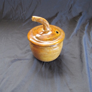 以下が含まれることがあります： 蓋と注ぎ口が付いた茶色の陶器の壺。壺は光沢のある仕上げで、渦巻き模様が施されています。