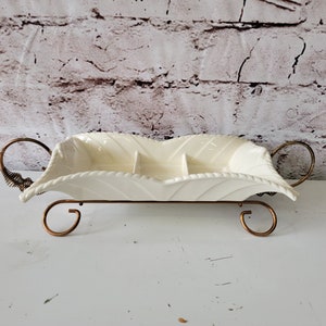 May include: White ceramic serving dish with three sections and a gold metal stand. The dish has a leaf-like design and the stand has decorative scrolls.