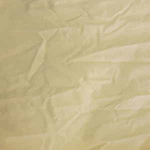 Puede incluir: Primer plano de una tela de color amarillo pálido con textura arrugada.