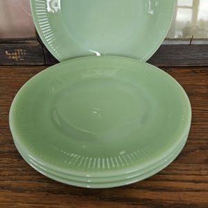 Puede incluir: Cuatro platos de vidrio verde claro apilados, con un diseño acanalado en los bordes. Están sobre una superficie de madera. Los platos tienen un acabado liso y brillante. Diámetro aproximado de 20 cm.