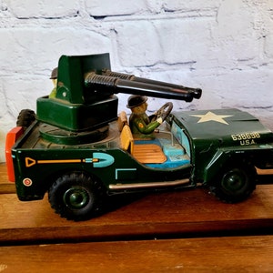May include: Green toy jeep with a rotating turret and two black cannons. The jeep has a star on the hood and the text "638698 U.S.A." printed on the side. Two toy soldiers are in the jeep.
