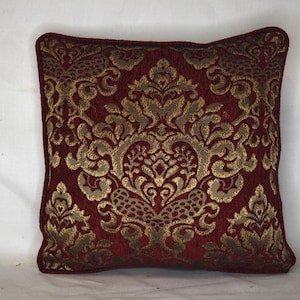 May include: A red and gold decorative throw pillow with a damask pattern.