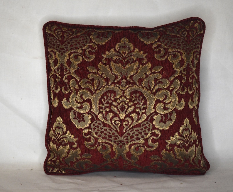 May include: A red and gold decorative throw pillow with a damask pattern.