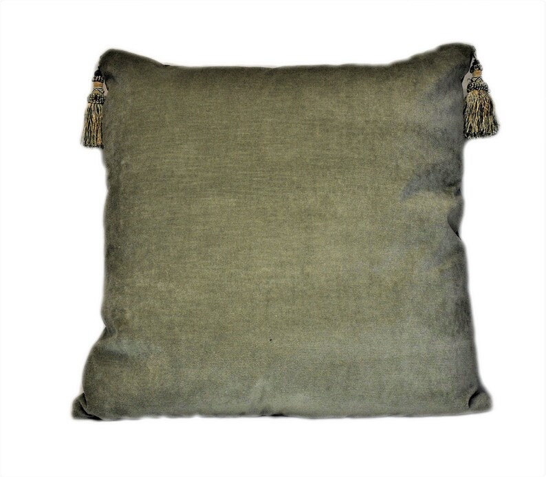 May include: A green velvet pillow with tassels on each corner. The pillow is a solid color and has a soft, plush texture.