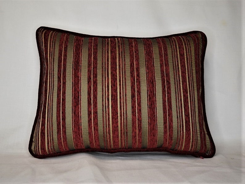 May include: A red and gold striped throw pillow with a dark brown border.