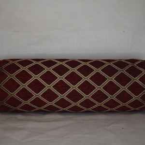 May include: A red cylindrical pillow with a gold diamond pattern.