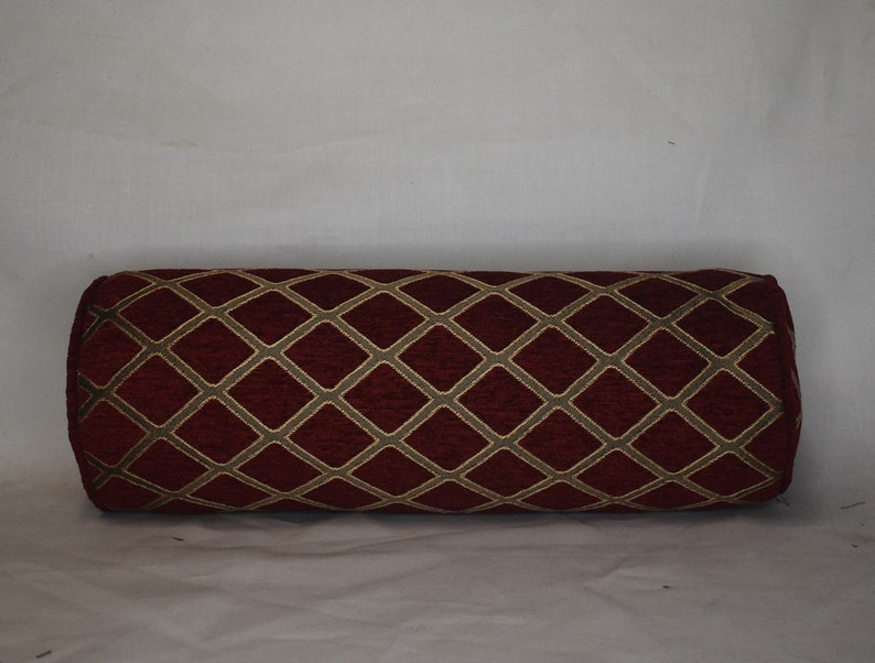 May include: A red cylindrical pillow with a gold diamond pattern.