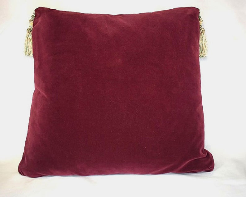May include: A burgundy velvet pillow with gold tassels on each corner.