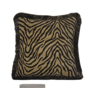 May include: A square throw pillow with a black and brown zebra print pattern. The pillow has a black fringe border.