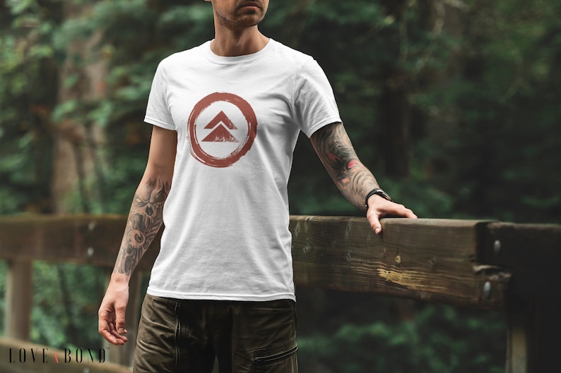 May include: White t-shirt with a red circle and a stylized symbol of two triangles inside. The symbol is reminiscent of a mountain range.