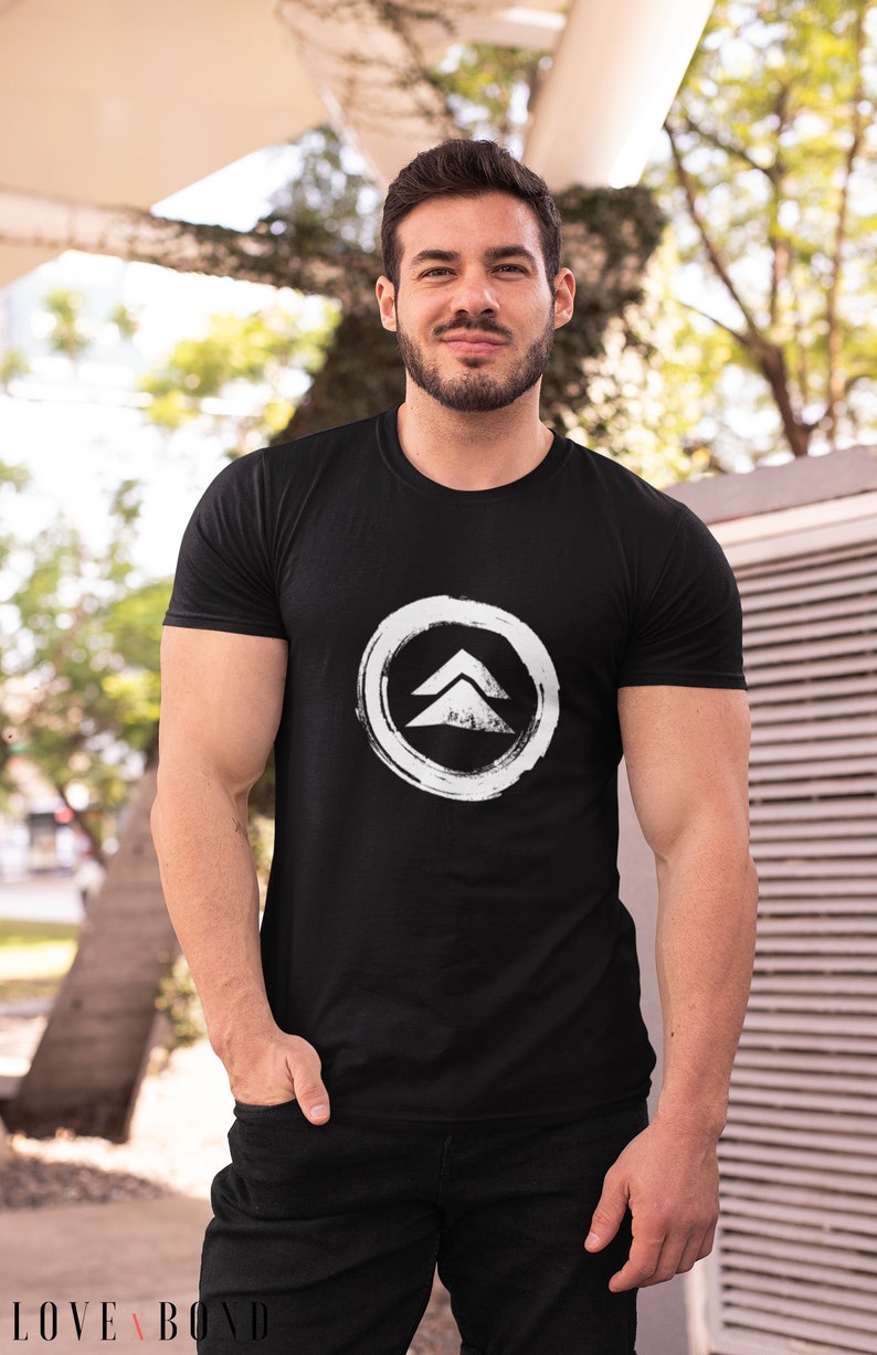 May include: A black t-shirt with a white graphic of a stylized arrow in a circle. The arrow is pointing upwards.