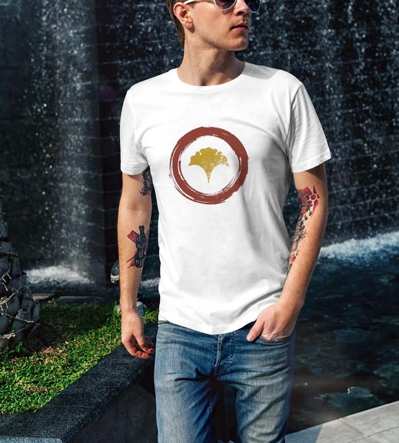 Pu&ograve; includere: Maglietta bianca con un cerchio rosso e un design a foglia di ginkgo giallo.