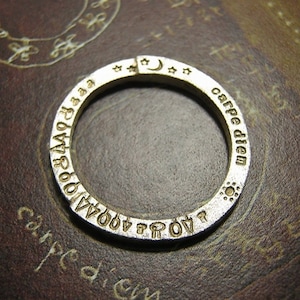 May include: A silver ring inscribed with the words "carpe diem" and a crescent moon with stars on the side.