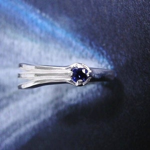 May include: A silver ring with three bands and a small blue gemstone.