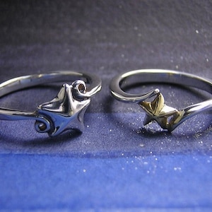 以下が含まれることがあります： 星形のデザインの銀の指輪が2つ。1つの指輪は銀の星、もう1つの指輪は金の星です。