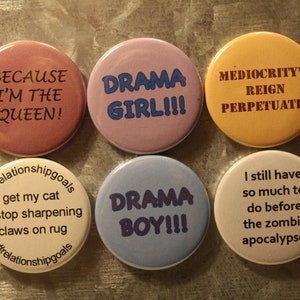May include: Six round buttons with various sayings on them. The buttons are pink, purple, yellow, beige, blue, and white. The sayings on the buttons are "Because I'm the Queen!" "Drama Girl!!!" "Mediocrity's Reign Perpetuates" "#relationshipgoals get my cat to stop sharpening claws on rug #relationshipgoals" "Drama Boy!!!" and "I still have so much to do before the zombie apocalypse."