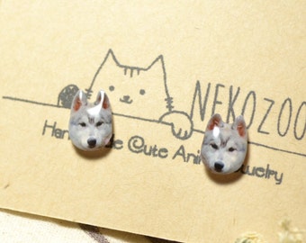 May include: A pair of silver stud earrings featuring a wolf face design. The earrings are displayed on a card with the text "NekoZoo Handmade Cute Animal Jewelry".