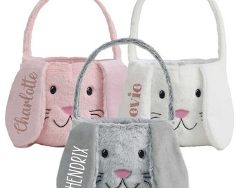 May include: Three plush bunny-shaped Easter baskets with personalized names. The baskets are pink, white, and gray. The names are Charlotte, Evie, and Hendrix.