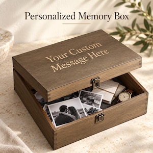 以下が含まれることがあります： Your Custom Message Hereと刻印された蓋付きの長方形のダークブラウンの木製メモリーボックス。箱は開いており、中には白黒写真、折りたたまれた紙、腕時計が入っています。