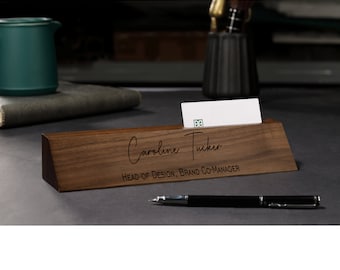 Puede incluir: Una placa de nombre de escritorio de madera con el texto "Caroline Tucker, Head of Design, Brand Co-Manager" grabado en ella.