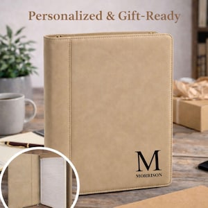 Peut inclure: Porte-documents zippé en similicuir beige avec le texte "Personnalisé et prêt à offrir". Le portfolio porte une initiale noire "M" et le nom "Morrison". Un encart circulaire montre l'intérieur avec un bloc-notes.