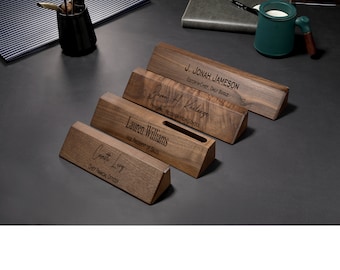 May include: Five wooden desk nameplates with engraved names and titles. The nameplates are angled and have a slot for a business card.