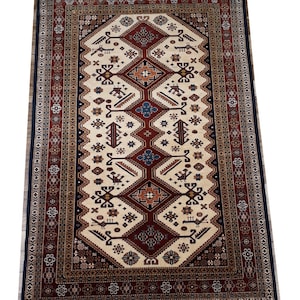 May include: A traditional rug with a cream background and intricate geometric patterns in shades of red, blue, and brown. The rug has a border with floral motifs.