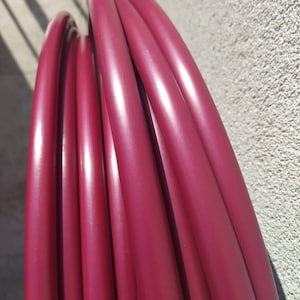 Puede incluir: Primer plano de un conjunto de aros de danza roja. Los aros están apilados y dispuestos en un patrón circular.