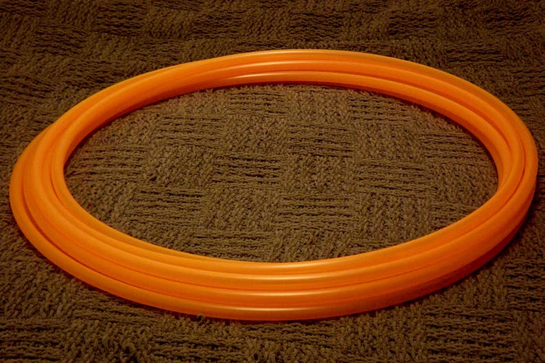 May include: A bright orange plastic hula hoop with multiple layers.
