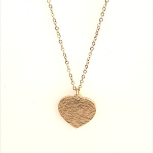 May include: A gold chain necklace with a hammered heart pendant.
