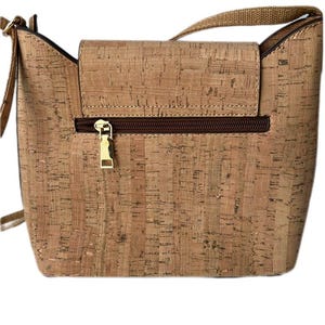 May include: A light brown cork crossbody bag with a gold zipper and a brown strap.