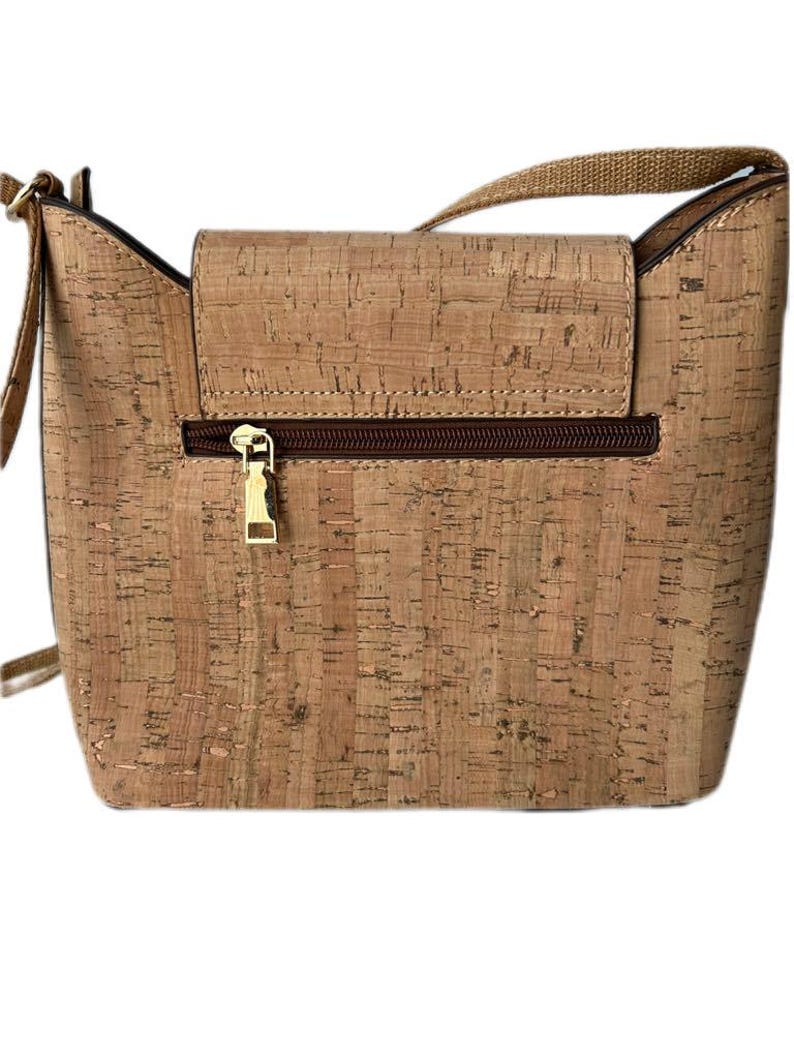 May include: A light brown cork crossbody bag with a gold zipper and a brown strap.