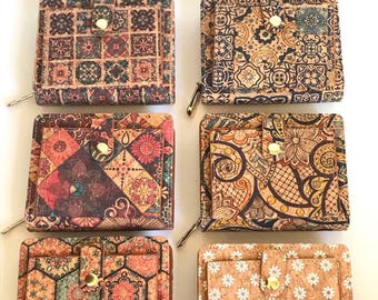 Peut inclure: Six portefeuilles carrés en liège, chacun arborant un motif imprimé distinct. Les designs incluent divers motifs géométriques, floraux et inspirés de carreaux dans des tons de brun, rouge, bleu et jaune. Chaque portefeuille a une fermeture à pression.
