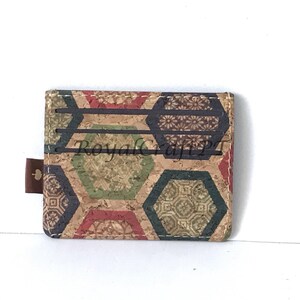 May include: A cork wallet with a geometric pattern in shades of brown, green, red, and blue. The wallet has six card slots and a small flap with a leaf design.