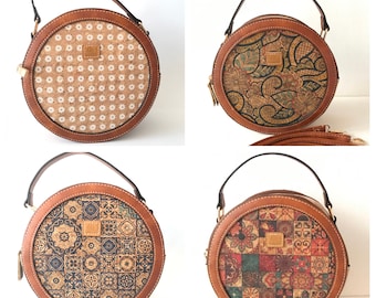 May include: Four round cork handbags with different patterns. The handbags have brown leather straps and a brown leather trim. The patterns include a white floral design, a paisley design, a geometric tile design, and a colorful patchwork design.