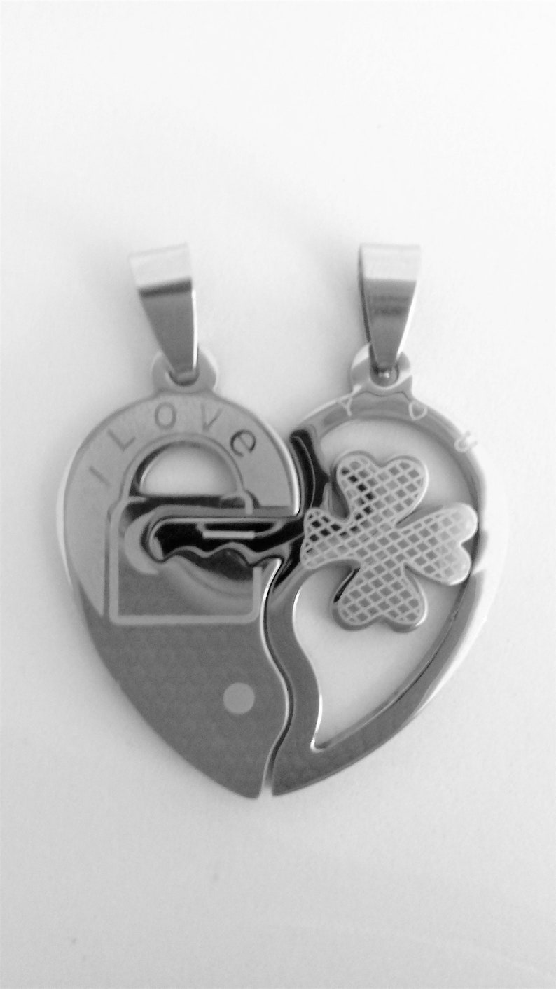 May include: Two silver heart-shaped pendants that fit together. One pendant has the words "I LOVE" and a padlock design. The other pendant has a four-leaf clover design.