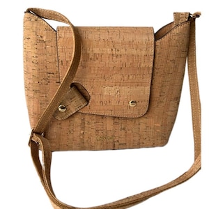 May include: A light brown cork crossbody bag with a gold logo that reads "CORKCIO".