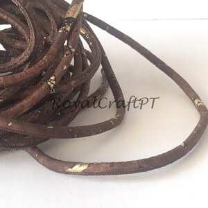 Pu&ograve; includere: Cordoncino in sughero marrone con accenti dorati. Il cordoncino &egrave; arrotolato a spirale.