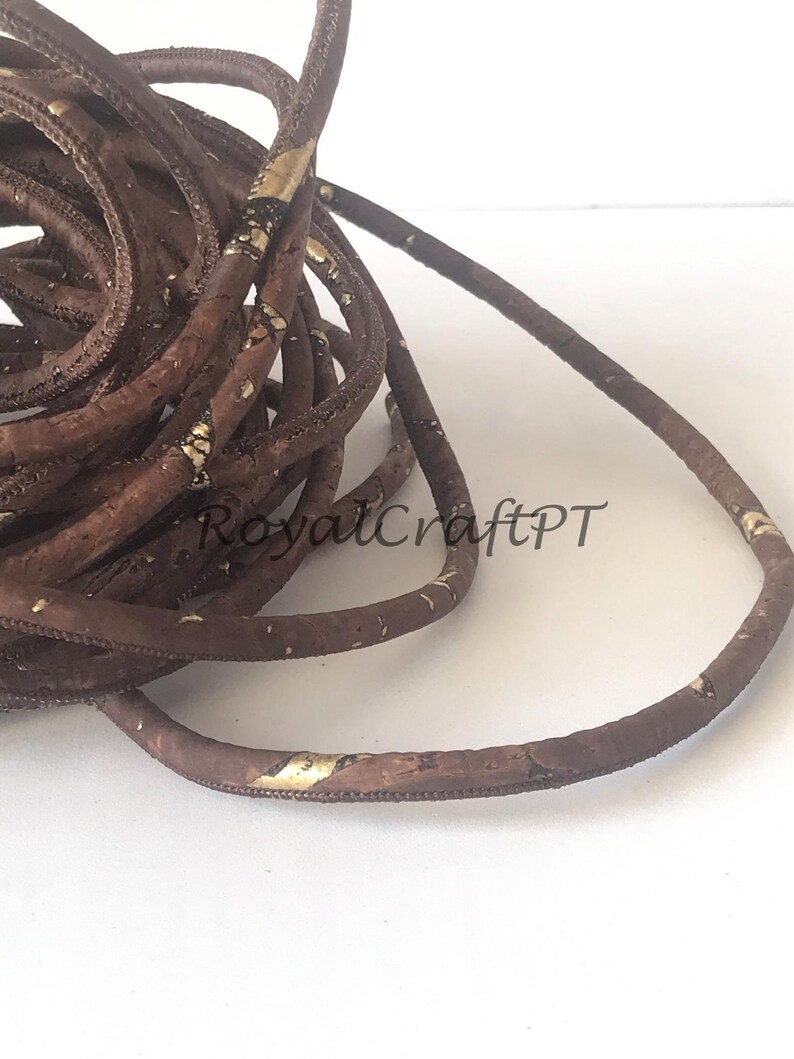 Pu&ograve; includere: Cordoncino in sughero marrone con accenti dorati. Il cordoncino &egrave; arrotolato a spirale.