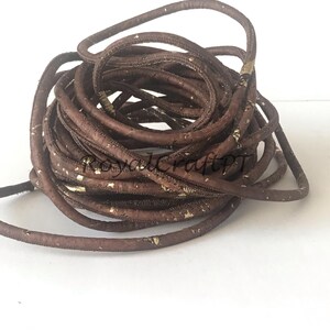 Pu&ograve; includere: Un cordoncino marrone con macchie dorate. Il cordoncino &egrave; fatto di sughero ed &egrave; spesso circa 6 mm.