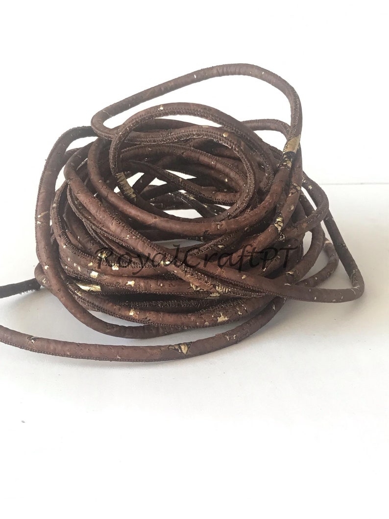 Pu&ograve; includere: Un cordoncino marrone con macchie dorate. Il cordoncino &egrave; fatto di sughero ed &egrave; spesso circa 6 mm.