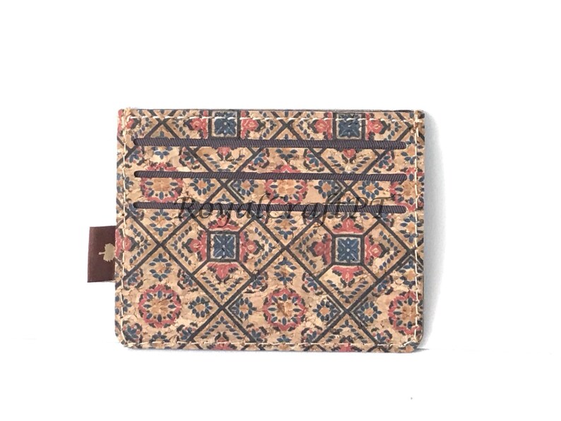 May include: A brown cork wallet with a patterned design featuring red, blue, and white geometric shapes. The wallet has multiple card slots and a brown leather strap.