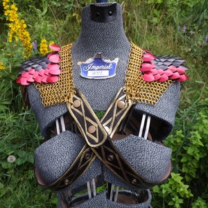 May include: A medieval-style chest armor on a mannequin. The armor features red and black shoulder scales, gold chainmail, and black leather straps with gold accents. A blue and white tag reads "Imperial".