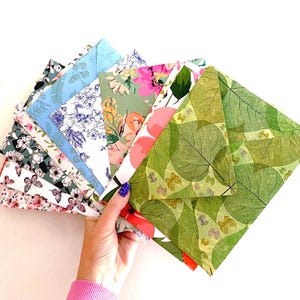 May include: A collection of square envelopes featuring a variety of colorful patterns, including green leaf prints with small butterflies, floral designs in pink and blue, and black and white butterfly motifs, fanned out in a layered arrangement.