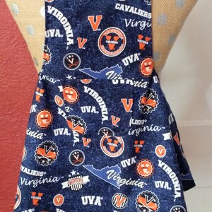 May include: A blue and orange apron with a repeating pattern of the University of Virginia logo, the words "UVA", "Virginia", and "Cavaliers", and a silhouette of the state of Virginia.