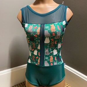 Op de afbeelding: Een groene maillot met een mesh-paneel aan de voorkant. De maillot heeft een kerstkattenprint met rode en witte accenten.