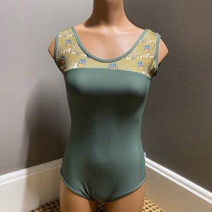 Op de afbeelding: Een groene maillot met een ronde hals en een gepatroneerd juk. Het juk is lichtbruin met een geometrisch patroon in blauw, oranje en geel.