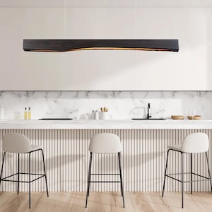 Linear wooden pendant light turned on in a modern interior, casting warm ambient lighting that creates a cozy atmosphere in a dining area.